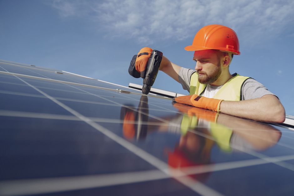 Professional solar panel installer smiling while working on a residential roof